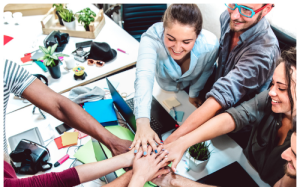 A team of employees are putting their hand in to signify togetherness.
