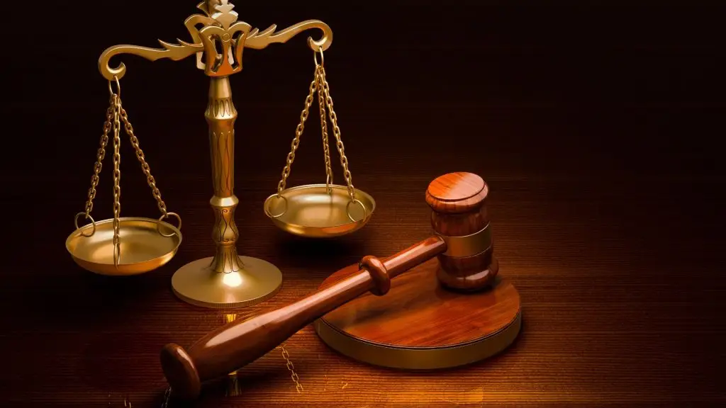 Brass weighing scales next to a wooden judge’s gavel — representing health and safety litigation and legal responsibility.