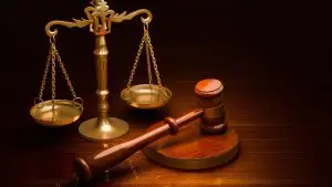 Brass weighing scales next to a wooden judge’s gavel — representing health and safety litigation and legal responsibility.