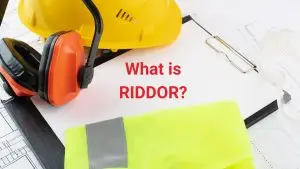 High-visibility vest, hard hat, and hearing protection laid on a clipboard — representing workplace safety and RIDDOR compliance.