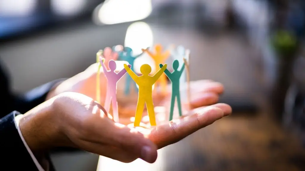 Paper cut-out figures with arms raised in a circle, sitting on open hands — representing fractional learning and development support.