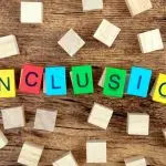 Wooden blocks on a table spelling out “Inclusion” in bright colours — representing neurodiversity and inclusion in the workplace.