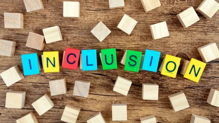 Wooden blocks on a table spelling out “Inclusion” in bright colours — representing neurodiversity and inclusion in the workplace.