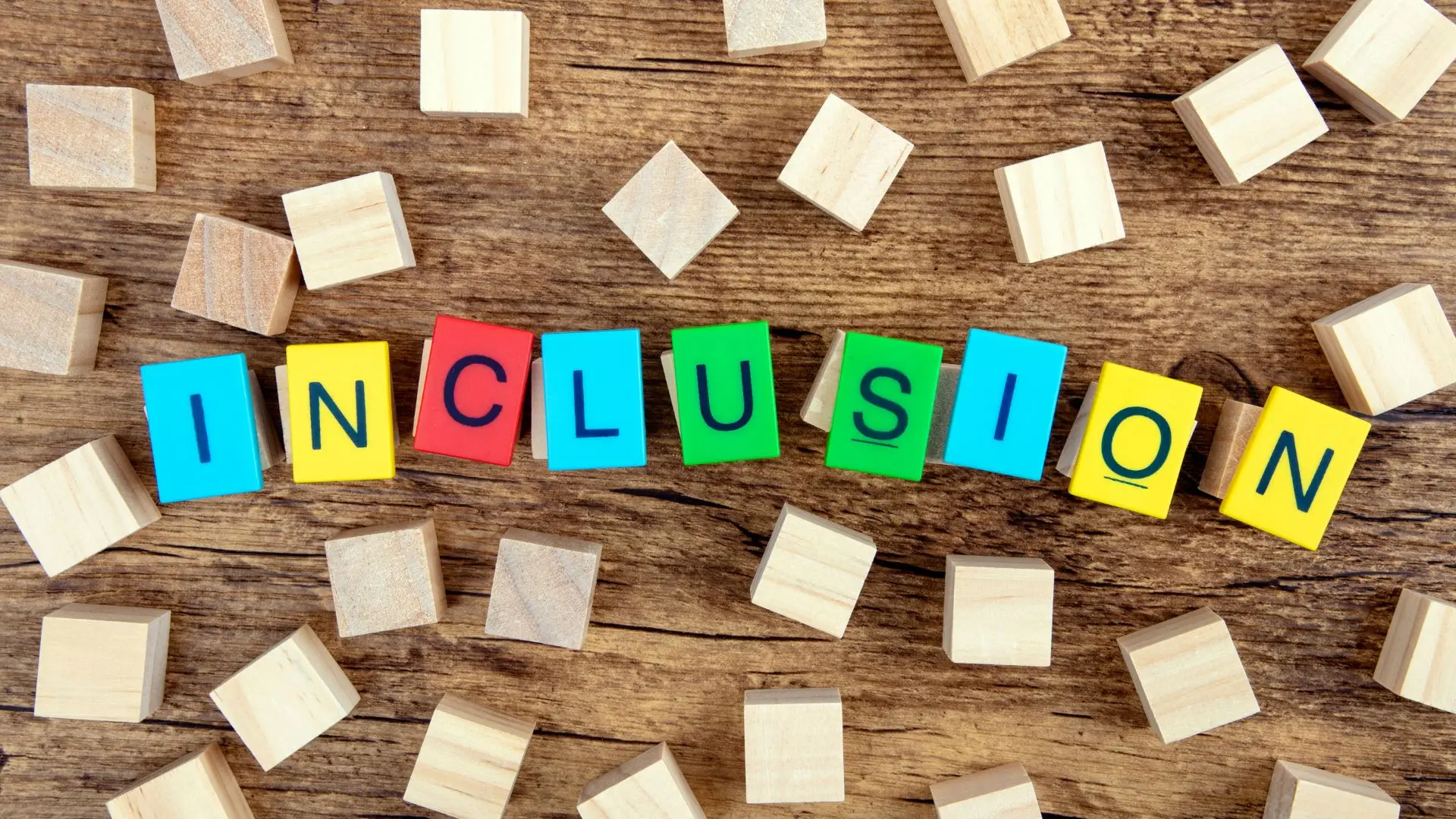 Wooden blocks on a table spelling out “Inclusion” in bright colours — representing neurodiversity and inclusion in the workplace.
