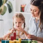 Mother and daughter playing with wooden blocks — representing support for parents of children with additional needs.